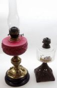 A Victorian Oil Lamp with clear glass chimney, opaque glass font, raised on a brass pedestal with