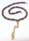 A high grade precious metal and polished Amethyst Bead Necklet, with yellow metal tasselled drop,
