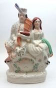 A 19th Century Staffordshire Figure Group, modelled as a Scots couple seated on a painted clock