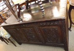 An 18th Century Oak Coffer with plank top, the front with three panels carved with stylised floral