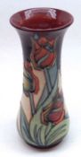 A Moorcroft Trumpet Vase of spreading circular form, decorated with a Tulip design on a red