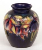 A Moorcroft Baluster Vase of tapering form, decorated with an Orchid design on a dark blue ground,