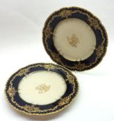 A pair of Sevres Plates, cream centres decorated within dark blue and gilt borders, 9 ½” diameter