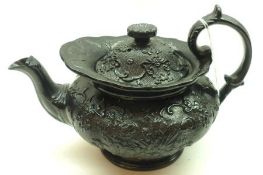 A 19th Century Black Glazed Teapot, moulded with scrolls and foliage etc (spout losses), 10” long