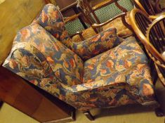 A floral upholstered Wing Armchair in the Georgian style, raised on front cabriole legs with ball