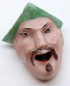 An unusual novelty Pen Stand modelled as the head of a Chinese man wearing a green peaked cap,