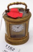 A Miniature Lacquered Brass Cased Carriage Clock of oval form, inset with four bevelled glass
