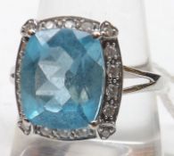A high grade precious metal cushion-shaped blue stone Ring, eighteen small brilliant cut Diamonds in