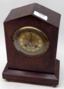 A Rosewood Cased Small Mantel Clock with arched top, over a circular brass face with black Roman