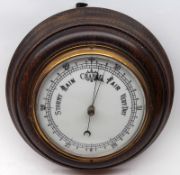 An early 20th Century Oak Framed Circular Aneroid Barometer, with opaque glass dial, brass bezel,