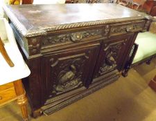 A late Victorian Heavily Carved Oak Sideboard fitted with two drawers with cup handles and two doors