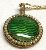 An unmarked yellow metal circular Pendant/Locket with green enamelled centre, Seed Pearls in