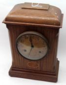 An early 20th Century Light Oak Cased Timepiece with moulded top over a circular face with Arabic