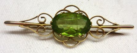 A mid-grade yellow metal scroll work design Bar Brooch with centre oval Tourmaline, stone size 15 mm