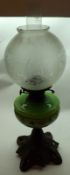 A Victorian Oil Lamp, frosted shade over a green glass font painted with flowers, raised on a