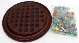 A Hardwood Solitaire Board, 7” diameter and a quantity of marbles