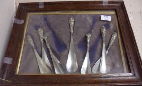 An Oak Surround and Glazed Frame holding seven assorted steel bladed and silver handled Shoe