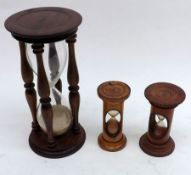 A group of three assorted Treen Framed Hourglasses, the largest 6 ½” high
