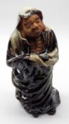 A Chinese Pottery Figure of a man wearing a treacle and ochre glaze robe (loss to tip of robe over