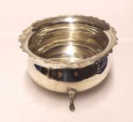 A large Edwardian Sugar Bowl of cauldron design with card cut rim and supported on three shell and