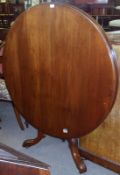 A Victorian Mahogany circular tilt-top Dining Table, raised on a balustered support, terminating