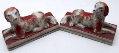 A pair of reproduction Staffordshire style Models of spaniels, decorated in iron red, 6” long