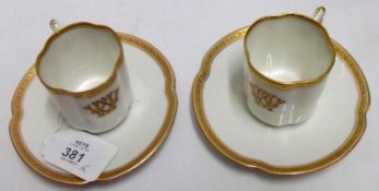 A pair of early 20th Century German Cabinet Cups and Saucers, decorated with gilt rims on a white