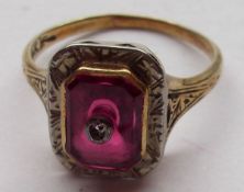 A mid-grade yellow metal Ring with shaped rectangular Ruby and small Diamond centre, the ruby