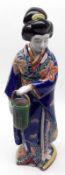 A 20th Century Oriental Figure of a young lady carrying a basket, decorated predominantly in