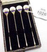 A 1930s cased set of four plated Cocktail Sticks with enamelled disc finials, inscribed “MAC”,