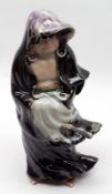 A Japanese Pottery Figure of a man wearing a hooded robe, decorated mainly in treacle with puce