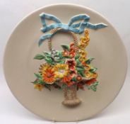 A Clarice Cliff Wall Charger, decorated with a raised design of coloured basket of flowers on a