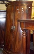 An 18th Century Mahogany Bow Front Corner Cupboard, the frieze inlaid with oval Sheraton style