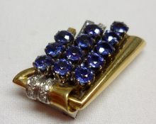An Art Deco style 18ct Gold and Platinum Clip set with twelve mid blue Sapphires, nine small