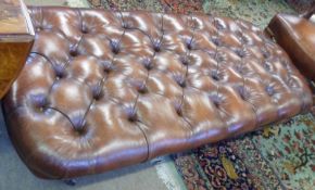 A large brown deep buttoned Leather rectangular Stool, raised on four turned legs, to castors, 63”