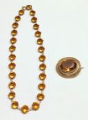 A white metal yellow stone Necklace together with an oval yellow stone Brooch (2).