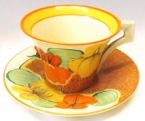 A Clarice Cliff Cup and Saucer, decorated with the “Nasturtium” pattern, on a Café au Lait ground.
