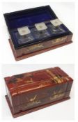 A lacquered cased set of three Oriental Ink Bottles with opaque glass stoppers, the iron red case