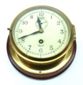 A 20th Century Brass circular Bulkhead Timepiece, on a Mahogany mount, 7” diam.