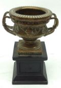 A small Brass model Urn, decorated with classical scenes, marked Made in England to base, standing