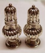 A pair of late Victorian small baluster Pepperettes with wrythen fluted baluster bodies, fluted