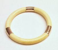 An Early 20th Century Ivory and yellow metal mounted plain circular Bangle, 69mm diameter