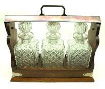 An Oak and Silver Plated Mounted Tantalus, fitted with three moulded glass decanters, 15” wide,