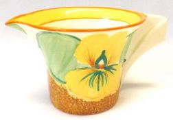 A Clarice Cliff Cream Jug with moulded handle, decorated with the “Nasturtium” pattern, on a Café au