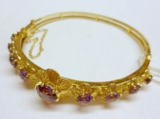 A hallmarked 9ct Gold Bangle featuring nine flower head panels, each set with a graduated