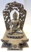 An Oriental base metal Model of a Tibetan Figure seated on a Podium before an Arch, decorated with