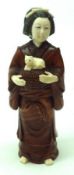 An unusual humorous Ivory or composition and Treen Oriental Figure of a girl carrying a basket