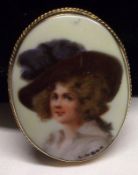 A yellow metal framed oval Brooch with ceramic panel featuring a partially painted portrait of a “