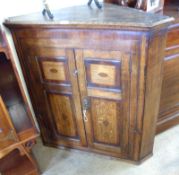 A 19th Century Oak and Mahogany banded two door Corner Cupboard, the two panelled doors each with