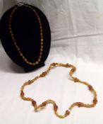 A long Amber Necklace of turned circular, square and natural beads, 64cm long together with a